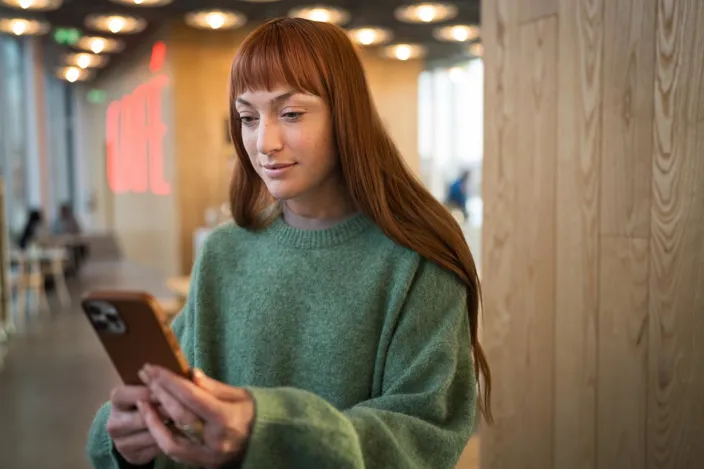 A young red hair woman using her phone in a cafe