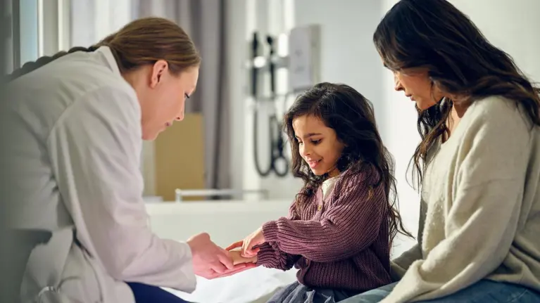A doctor examining a child with her mother