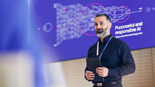 A Tietoevry employee giving a speech about Ai with Purposeful Ai message on the screen behind him