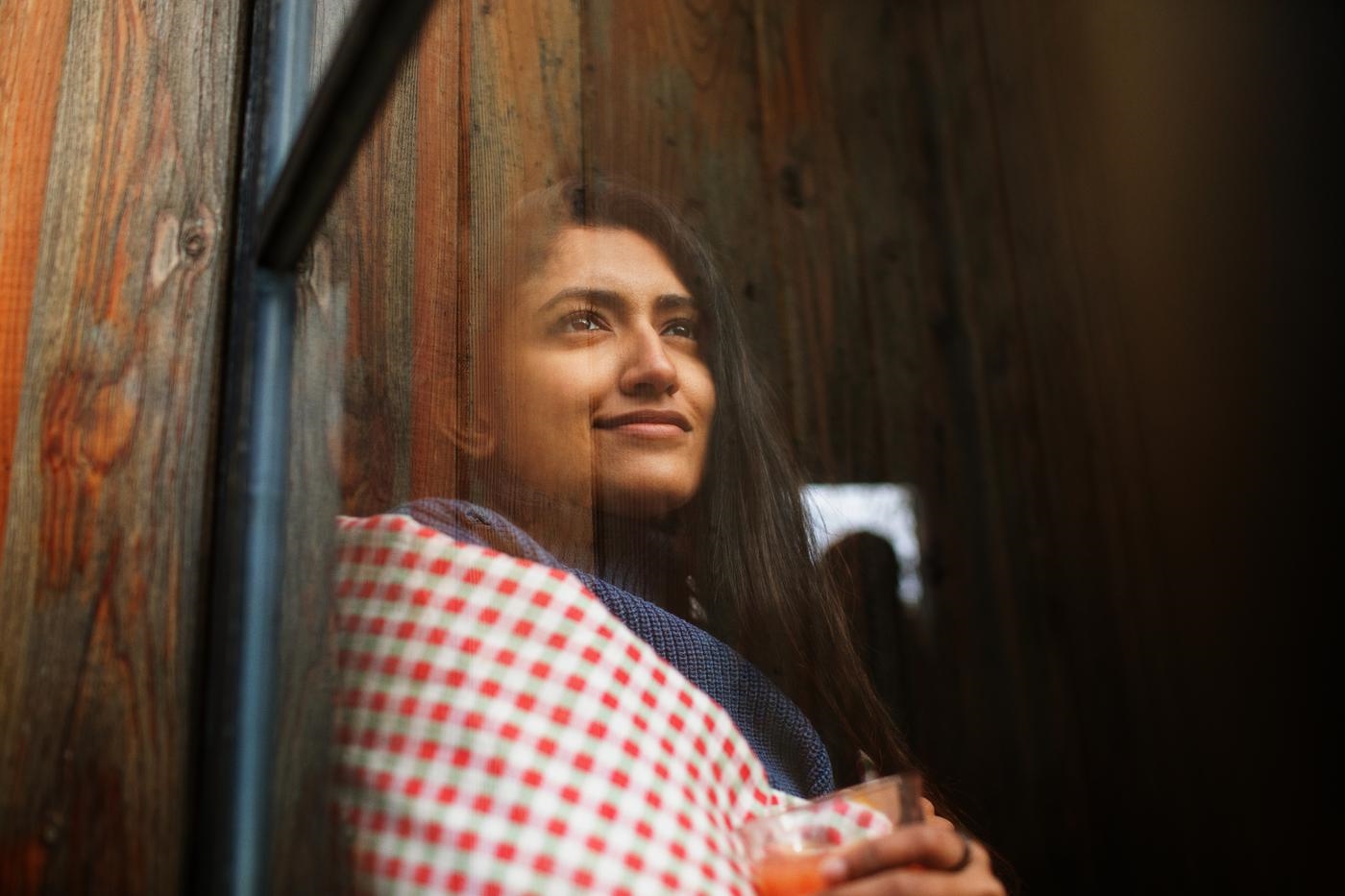 Thoughtful beautiful young woman looking out window with a glass in hand