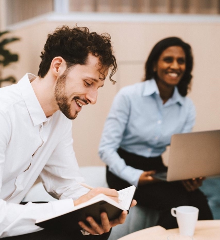 two people sitting in a meeting and smiling