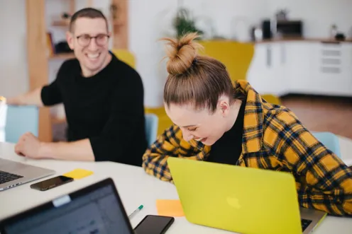 People laughing working on laptop in office