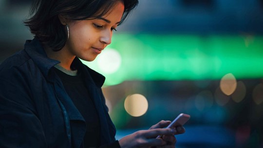 A young woman  is using her phone smiling