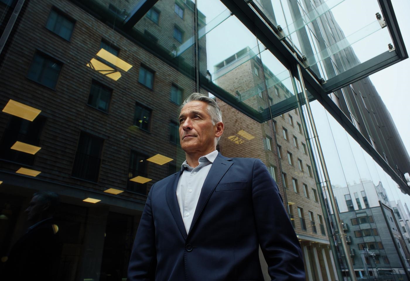 A man in a business suit in front of a modern office building