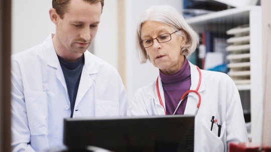 two medical professions looking at a computer screen