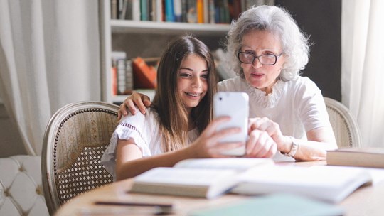 Studying girl showing grandma smartphone