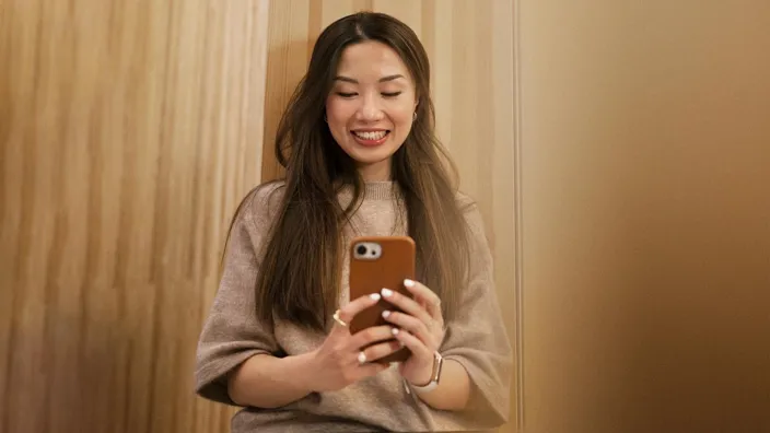 Young woman taking photo with her phone smiling siting in window