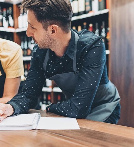 Couple of winery owners talking and writing in a textbook