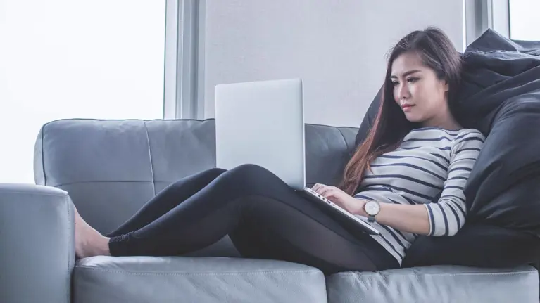 Woman sitting on a sofa, working with her laptop